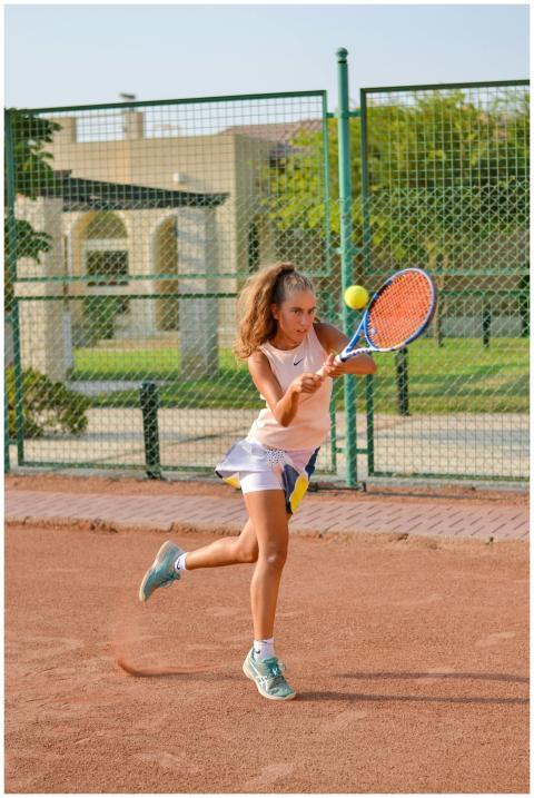 Energetic young female tennis player swings racket