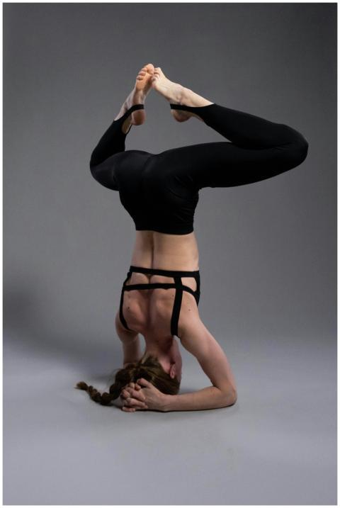 Woman executing an advanced yoga headstand in a st