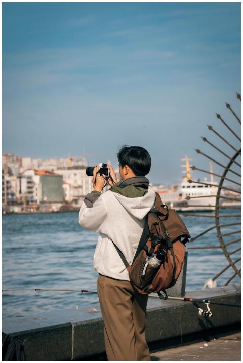 A person taking photos by the riverside in a city