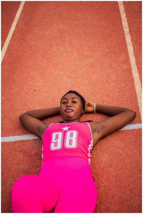 Athlete in pink sportswear relaxing on a track fie