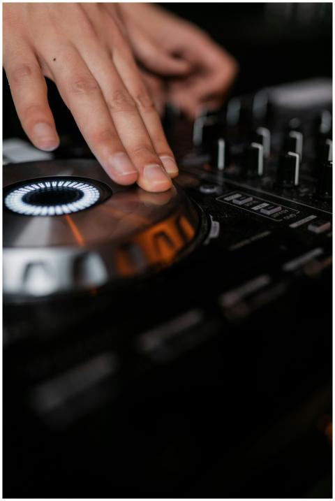 DJ's hand skillfully turning knobs on an illuminat