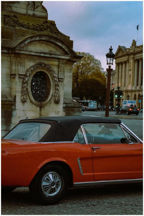 Classic red car parked by historic architecture in