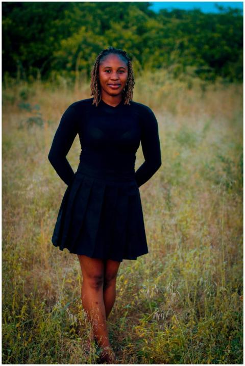 Portrait of a young woman in a black dress standin