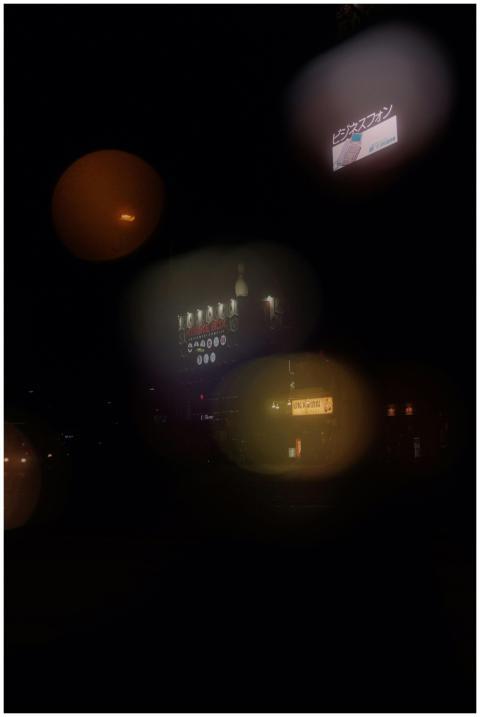 A city street at night with glowing billboards and