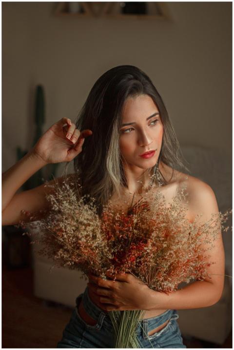 Woman poses indoors holding a bouquet of dried flo