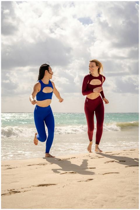 Two women in activewear jogging on a sunny beach w