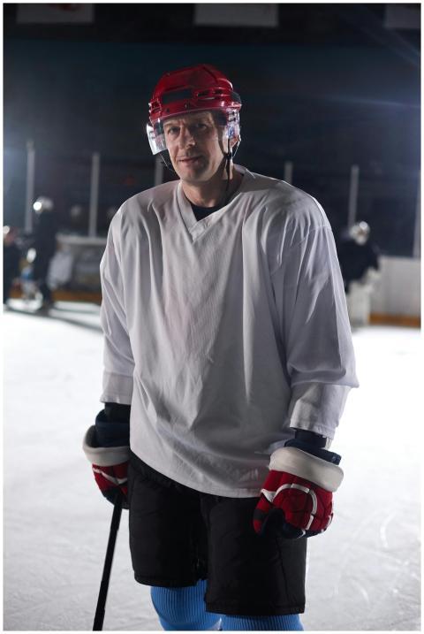 A male ice hockey player in sportswear poses on an