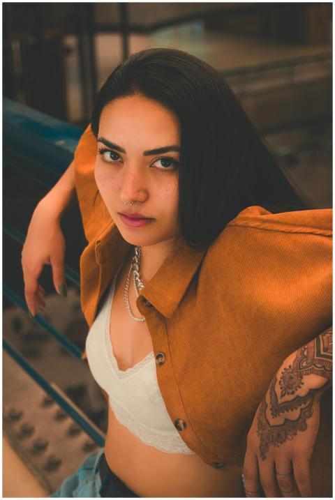 Fashionable woman posing confidently with henna ta