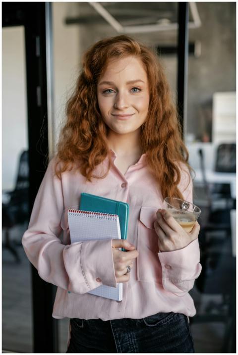 Young woman inside office holding a notebook and c