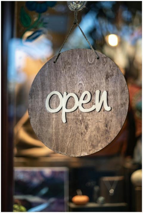 Close-up of a rustic wooden 'open' sign hanging in