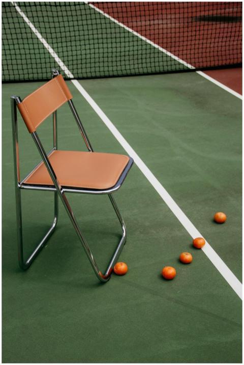A modern chair and mandarin oranges on a green ten