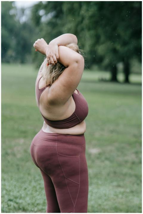 A woman in workout attire stretches her arms in a