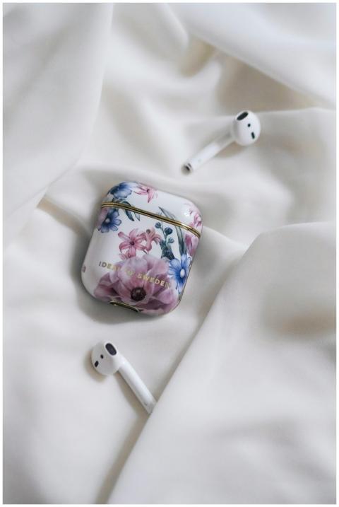 AirPods with a floral case set on soft white fabri