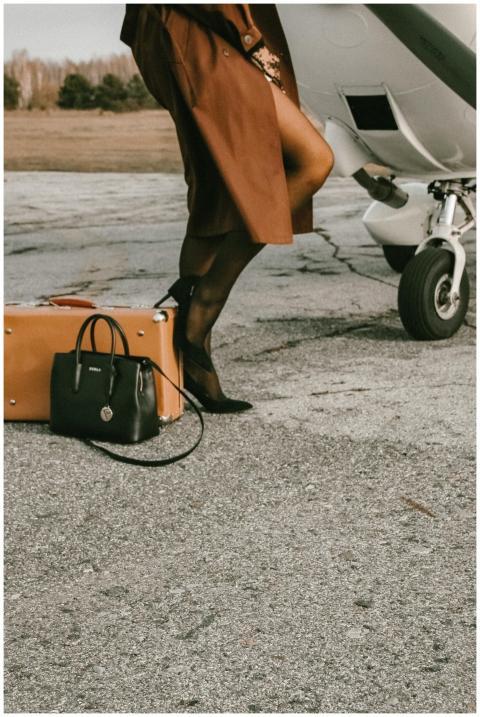Elegantly dressed woman beside a private plane wit