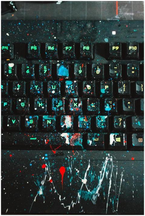 Close-up of a keyboard covered in vibrant paint sp