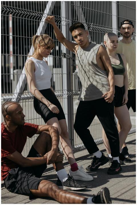 Five young adults in activewear pose against a met
