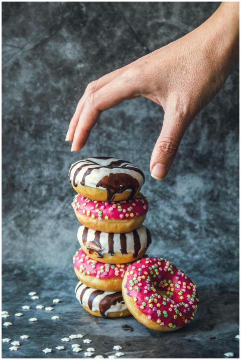 A hand reaches for a stack of colorful donuts with
