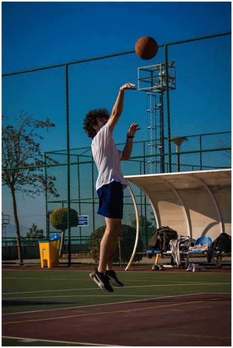 Young male basketball player mid-air shooting on a