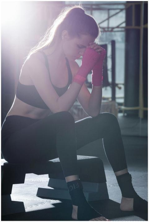 Woman in activewear sitting in gym with thoughtful