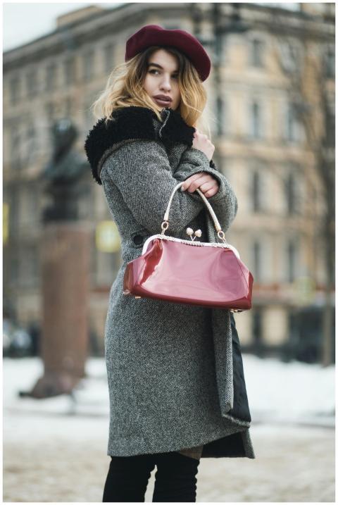 Stylish woman in winter coat and beret holding han