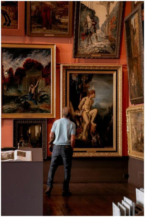 Man stands observing classic paintings in a Paris