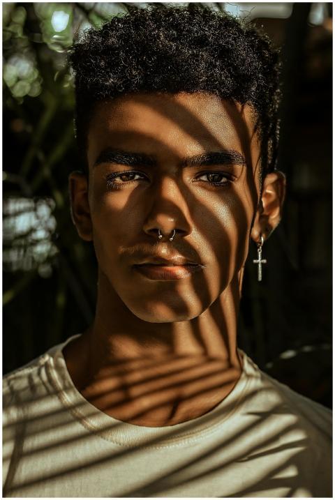 Stylish young man with shadows on face, wearing ea