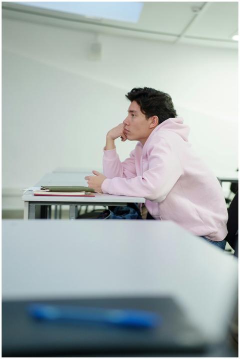 A thoughtful Asian boy in a pink sweatshirt sittin