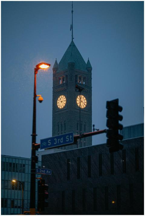 Illuminated clock tower in downtown cityscape at n