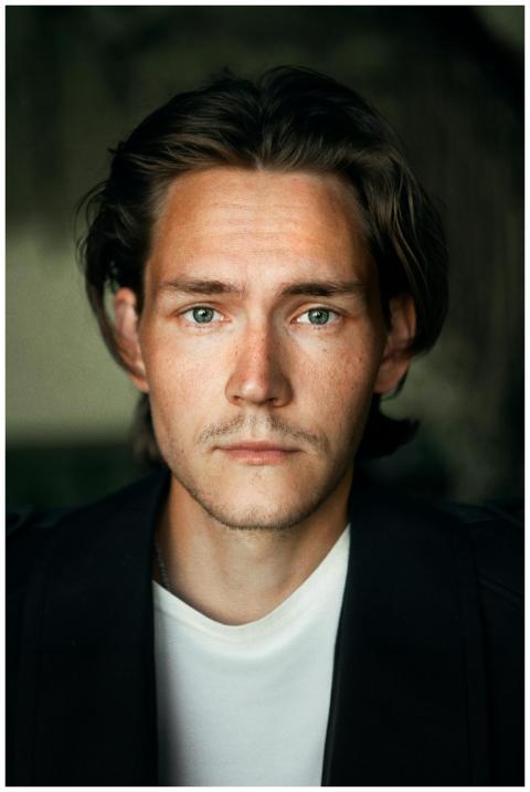 Close-up portrait of a young man with long brown h