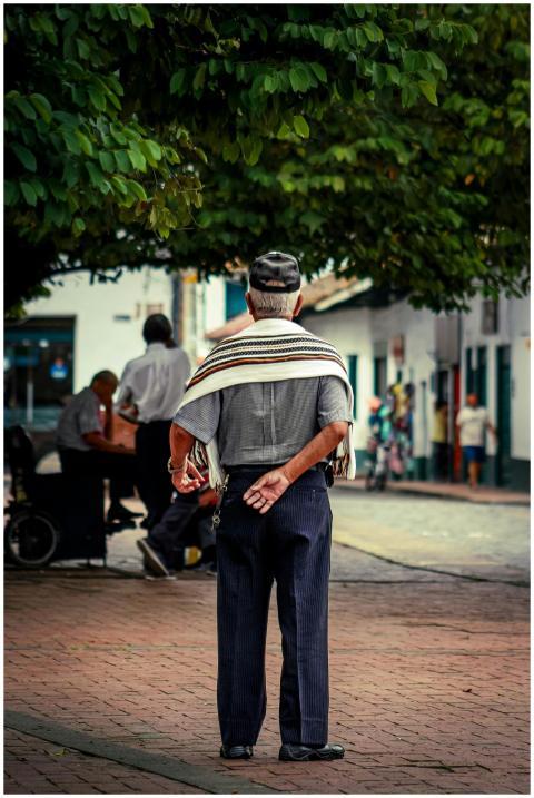An elderly man standing on a vibrant city street,