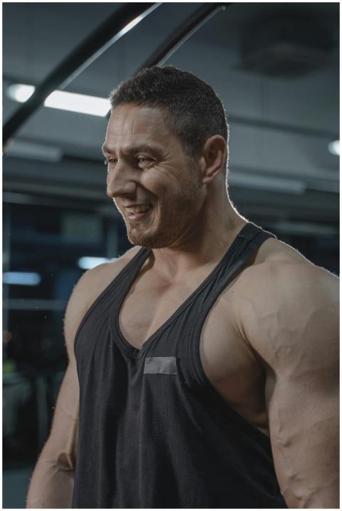 Fit man in a black tank top smiling during workout