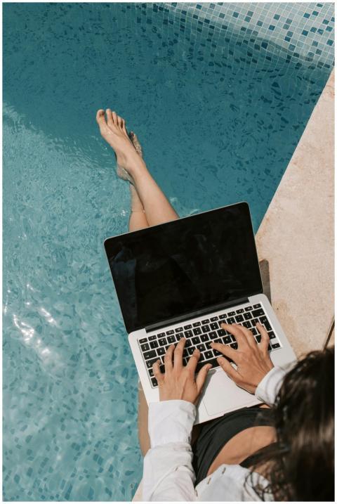 Woman working remotely on a laptop by the poolside