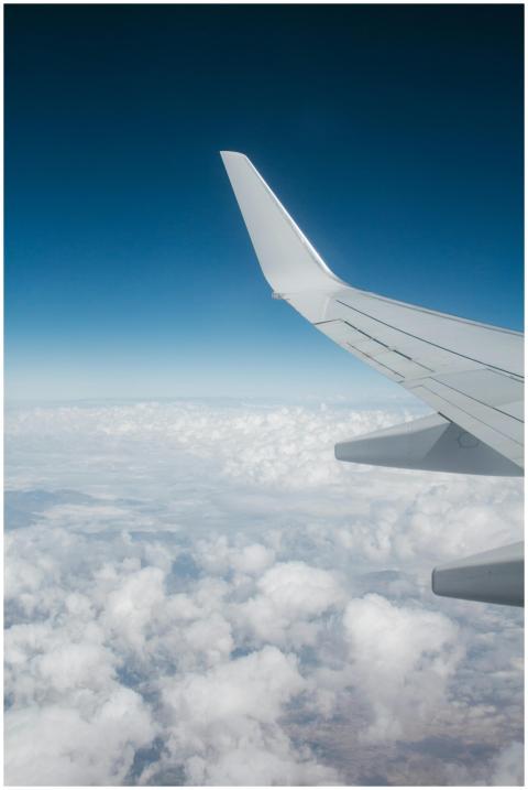 High-altitude view of airplane wing with white clo
