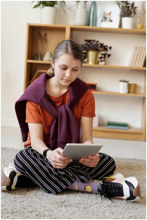 Teenage girl sitting on the floor using a tablet i