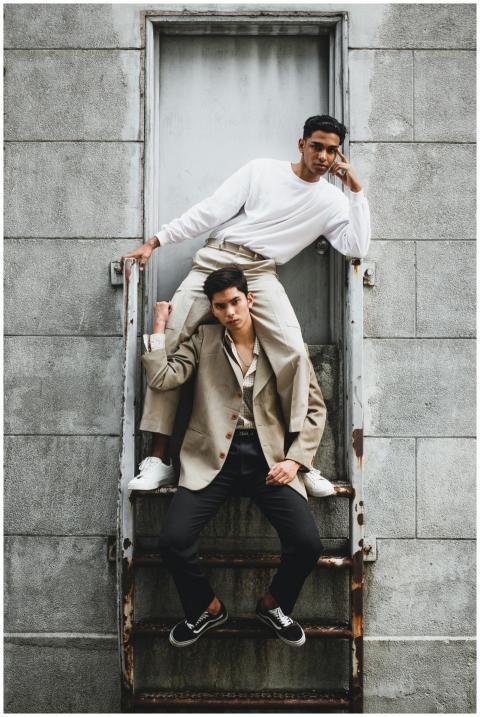 Two male models posing stylishly on a rusty stairc