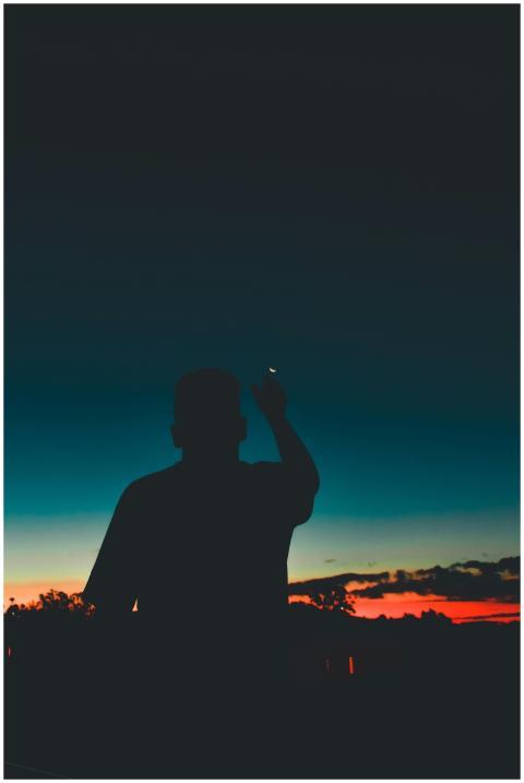 Silhouette of a man pointing at the night sky duri