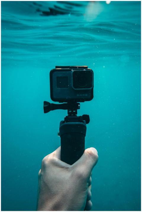 A hand holding an action camera underwater in Jeze