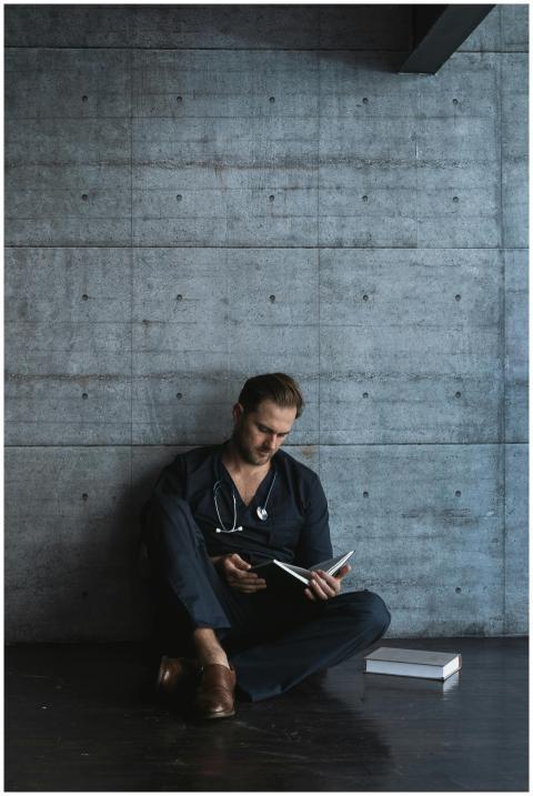Adult male doctor reading a book in a modern, mini