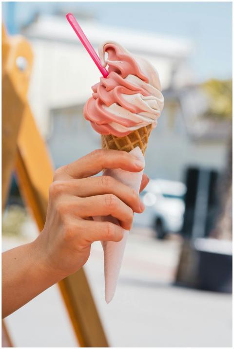 Close-up of a hand holding a strawberry and vanill