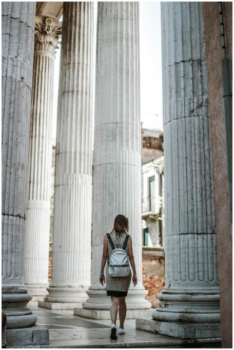 Woman walking among grand ancient stone columns in