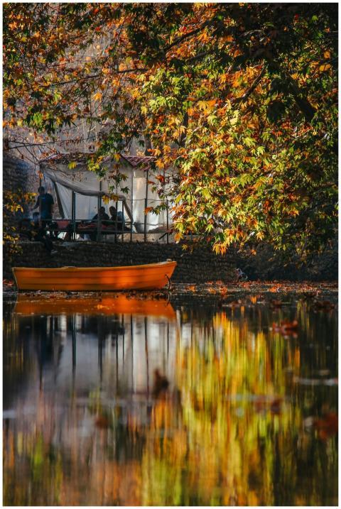 Tranquil autumn scene with a boat reflecting on wa