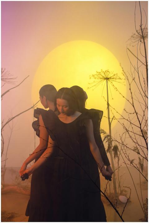 Three women in black dresses holding hands under a
