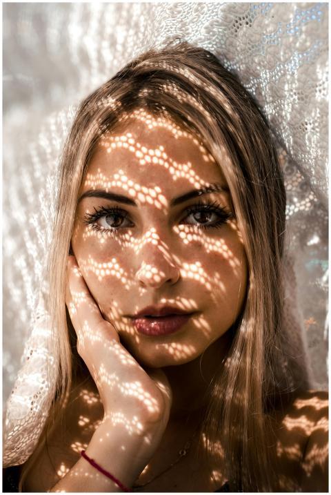 Close-up of a woman with intricate lace shadows on