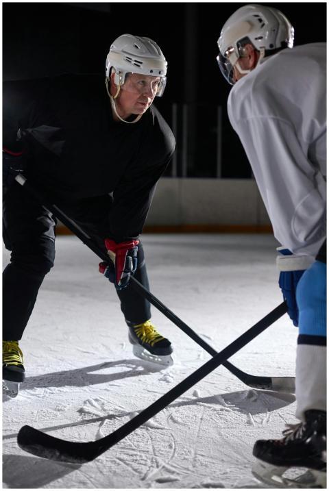 Two hockey players facing off at an indoor ice rin