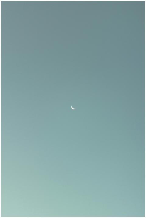 A serene crescent moon set against a clear sky dur