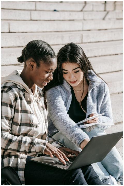 Two young women studying together on a campus stai