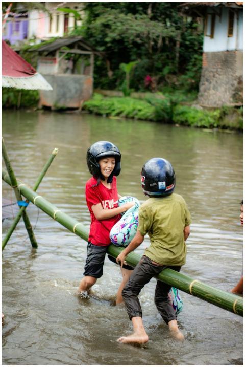 Kids in helmets enjoying play on a bamboo bridge o