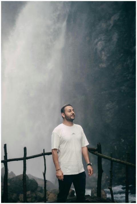 A man standing by the majestic Kapuzbaşı Waterfall
