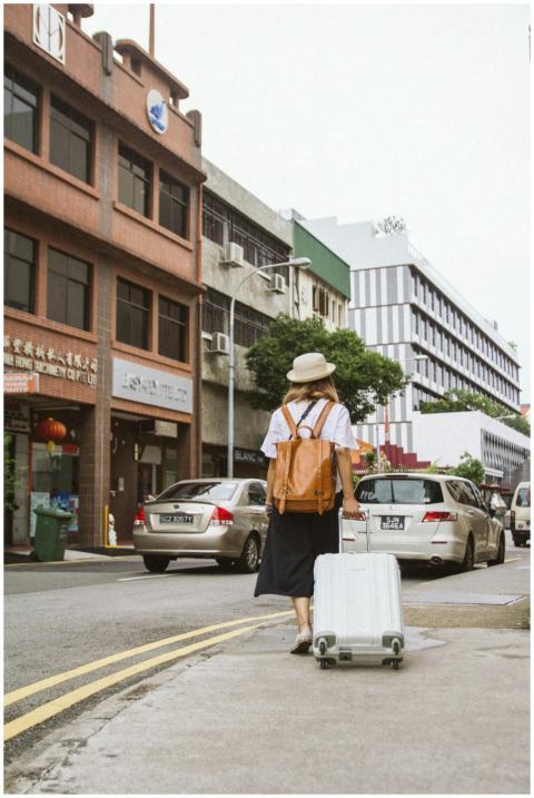 A woman with a suitcase and backpack walks down a