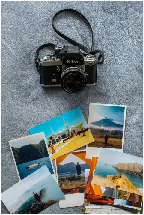 Old Nikon camera with various travel photos scatte